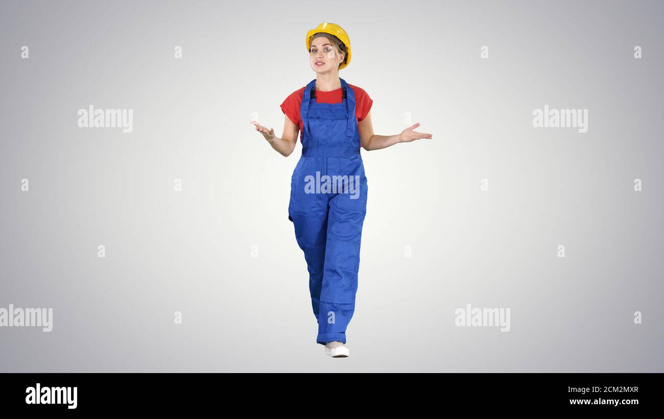 Cheerful female construction worker talking to camera on gradien Stock Photo