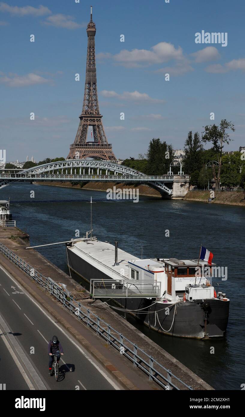 A man rides a bicycle on a bike path on the banks of the river Seine with the Pont Rouelle bridge and the Eiffel tower in the background in Paris during the outbreak coronavirus disease (COVID-19) in France, May 14, 2020. REUTERS/Gonzalo Fuentes Stock Photo