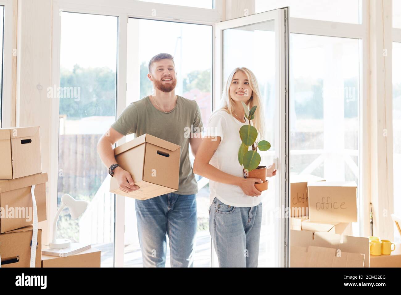 Happy young Couple Carrying Cardboard Boxes Into New Home On Moving Day ...