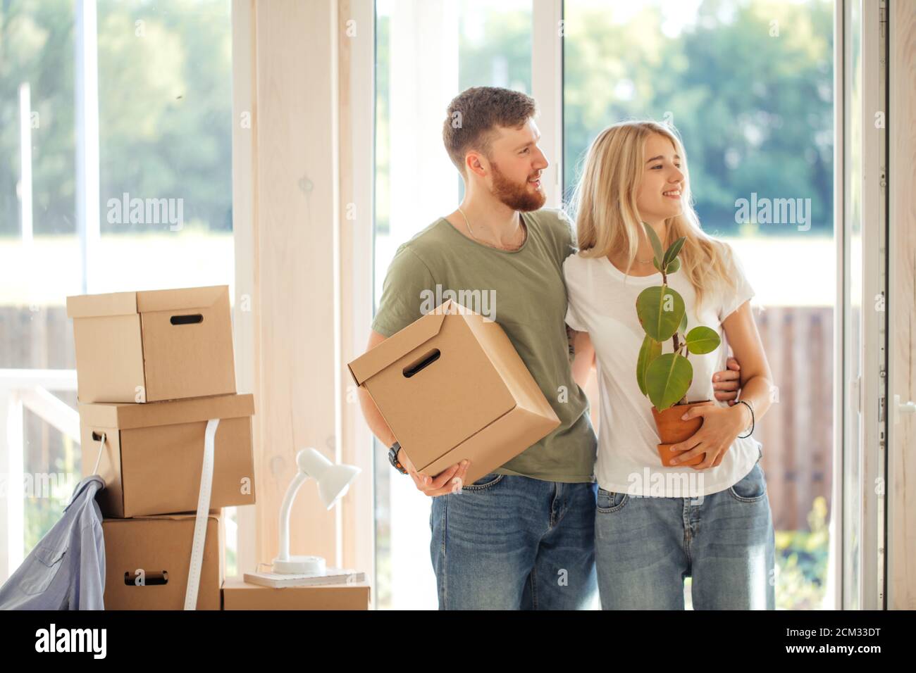 Happy young Couple Carrying Cardboard Boxes Into New Home On Moving Day ...