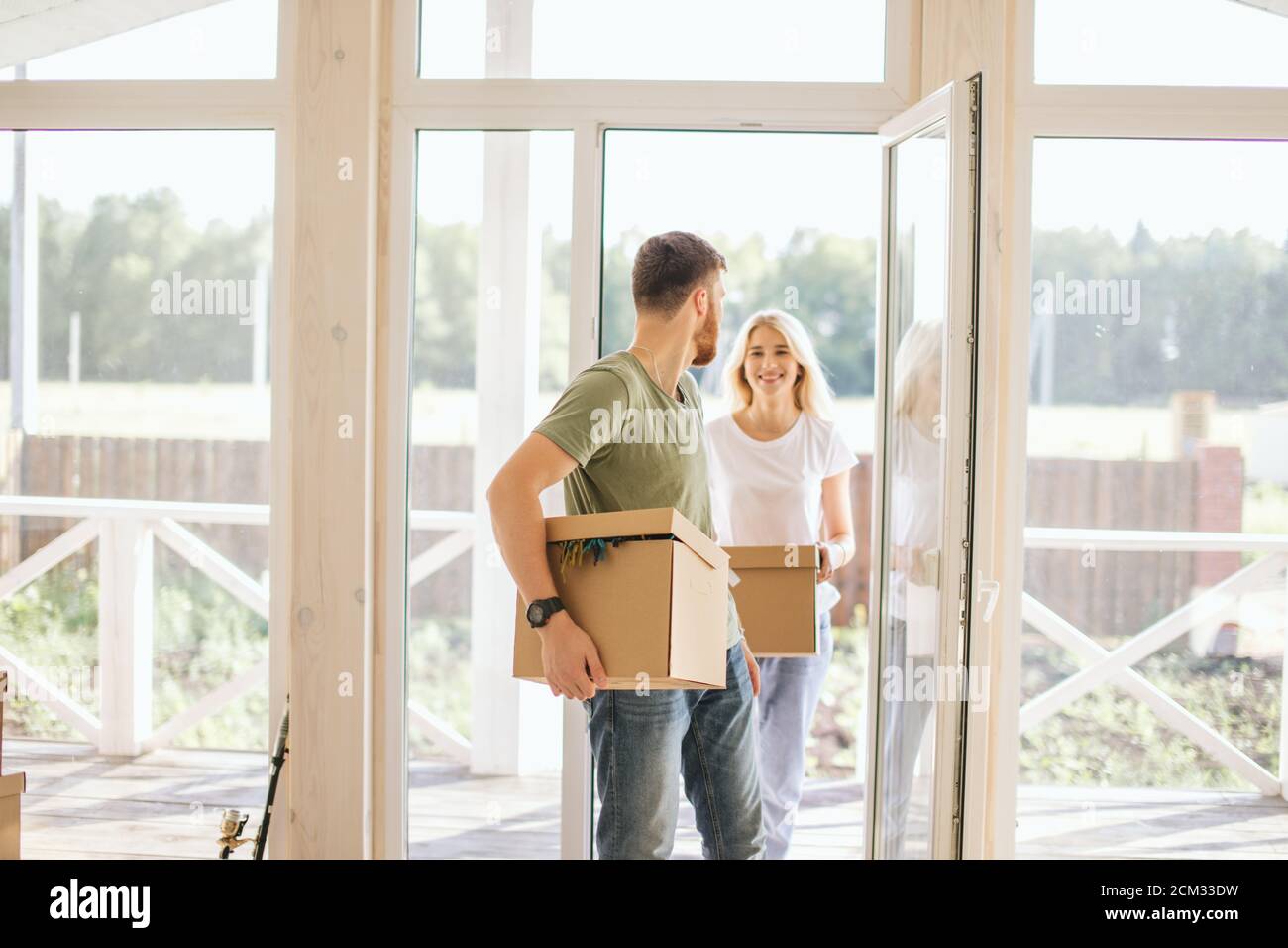 Happy young Couple Carrying Cardboard Boxes Into New Home On Moving Day ...