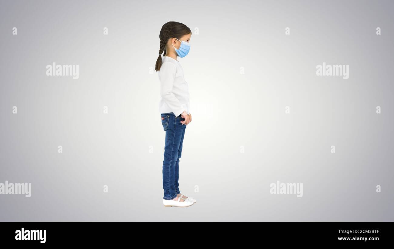 Little girl taking her face mask off and smiling at camera on gr Stock Photo