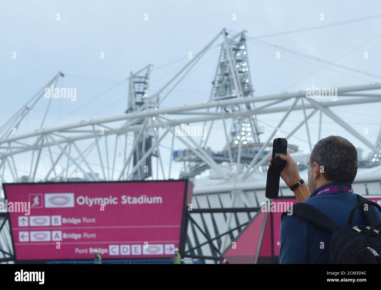 A worker records images using a phone outside the Olympic Stadium at the Olympic Park in Stratford, the location of the London 2012 Olympic Games, in east London July 20, 2012. REUTERS/Toby Melville  (BRITAIN - Tags: SPORT OLYMPICS) Stock Photo