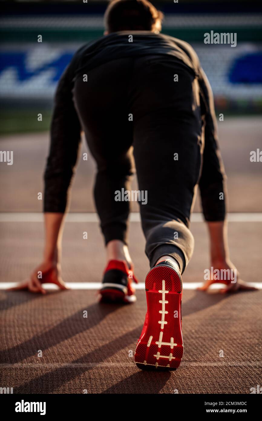 Back view of man feet in starting position for running on race track in