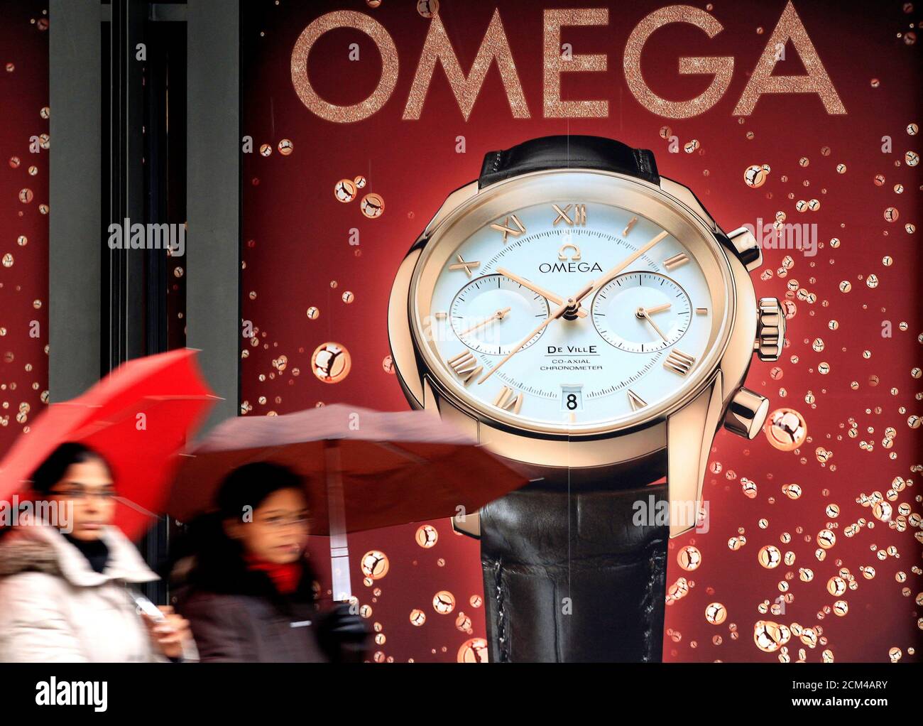 Women walk past an advertisement for Swiss watch manufacturer Omega in  Zurich February 4, 2013. Swatch Group SA is optimistic about growth  prospects for this year after the world's biggest watchmaker reported