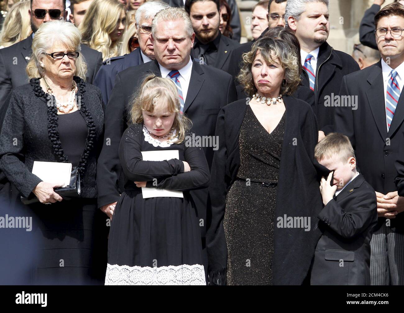 Renata Ford, her daughter Stephanie and son Doug Ford Junior stand outside  St James Cathedral with Doug Ford and his mother as the hearse leaves  carrying former mayor Rob Ford, in Toronto