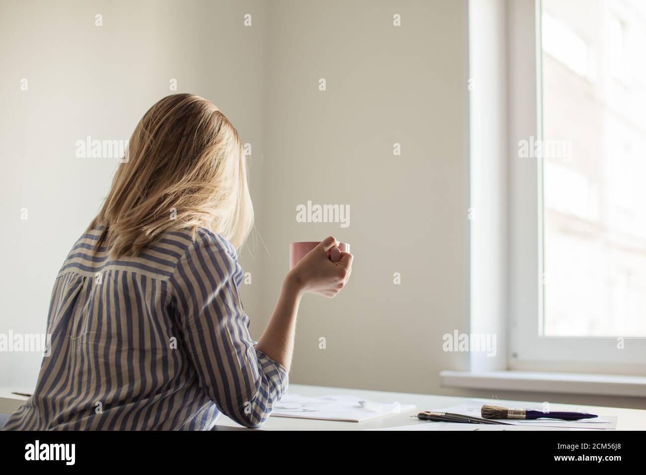 Close up photo of woman writing beautiful notes on paper on white desk while drink coffee or tea Stock Photo