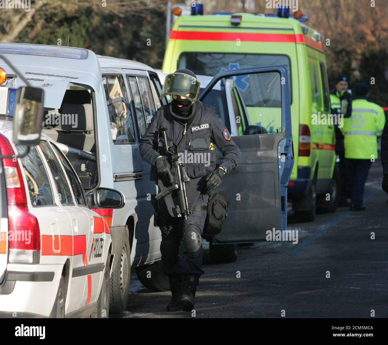 A Police Officer Patrols Along Ambulance And Police Cars Stationed Near The Spanish Consulate In Berne Where Hostages Were Taken By An Unknown Intruder A Police Officer Patrols Along A Row Of