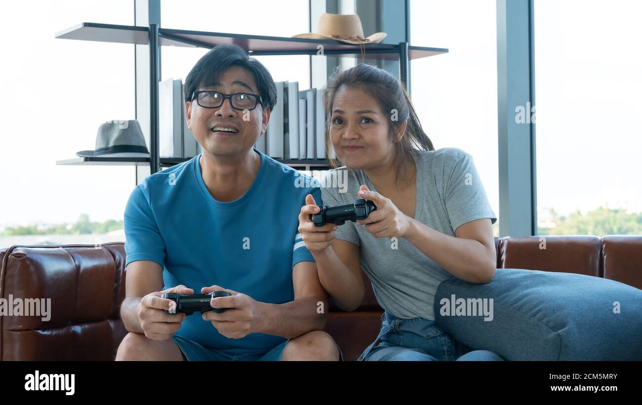 Old man and woman playing video game at home Stock Photo