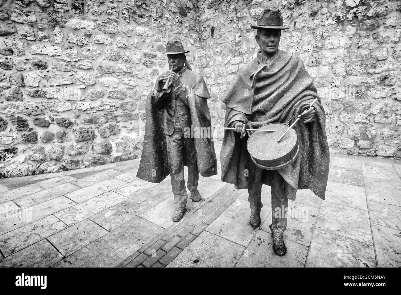 Front view of bronze statues showing traditional folk musicians playing folk music in front of a stoned wall in a street in Burgos, Spain. Stock Photo