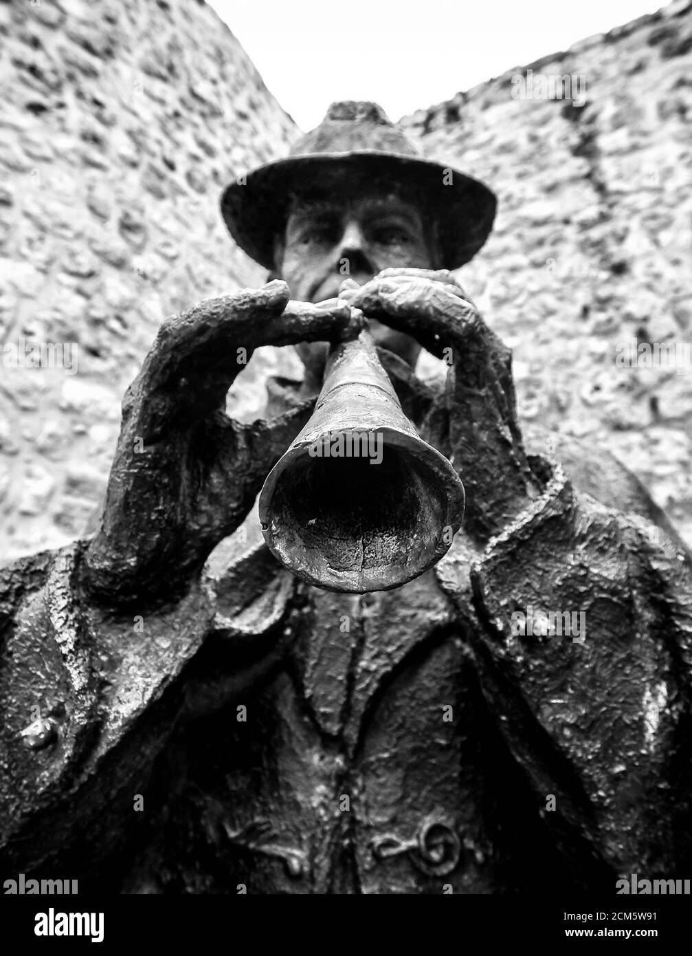 Bronze statue of a traditional folk musician playing a typical wind instrument called 'Dulzaina' in front of a stoned wall in Burgos, Spain. Stock Photo