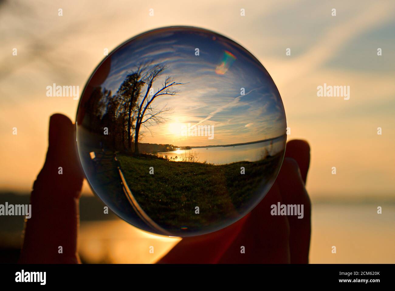 Reflection of sunset over water in a crystal ball, held by a hand Stock ...