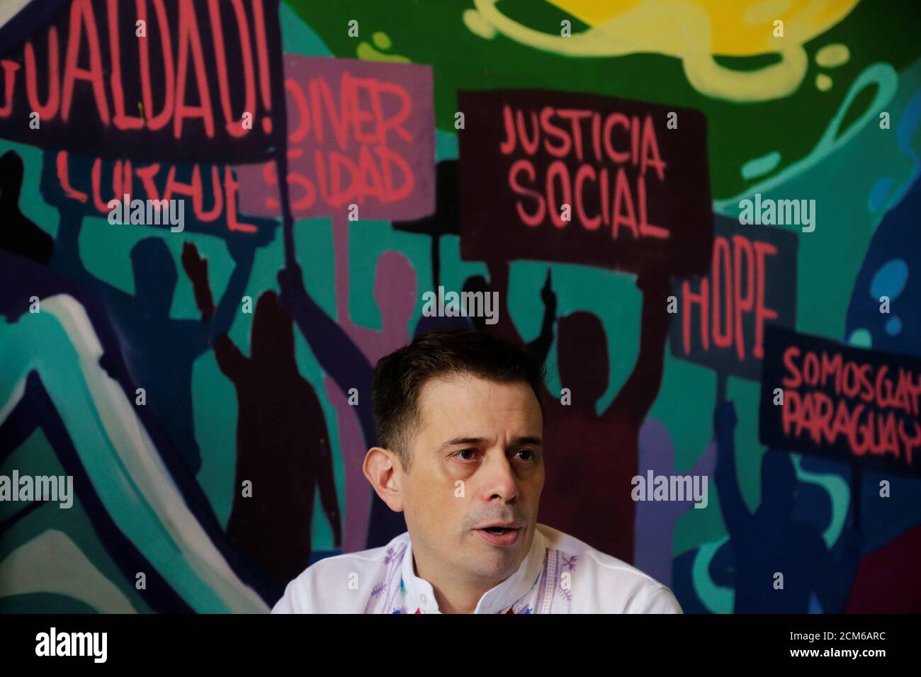 Simon Cazal, executive director of the organization SomosGay, talks to Reuters in Asuncion, Paraguay March 22, 2019. The writings on the wall read: 'Equality, Diversity, Social Justice and We are Gay Paraguay.' Picture taken March 22, 2019. REUTERS/Jorge Adorno Stock Photo
