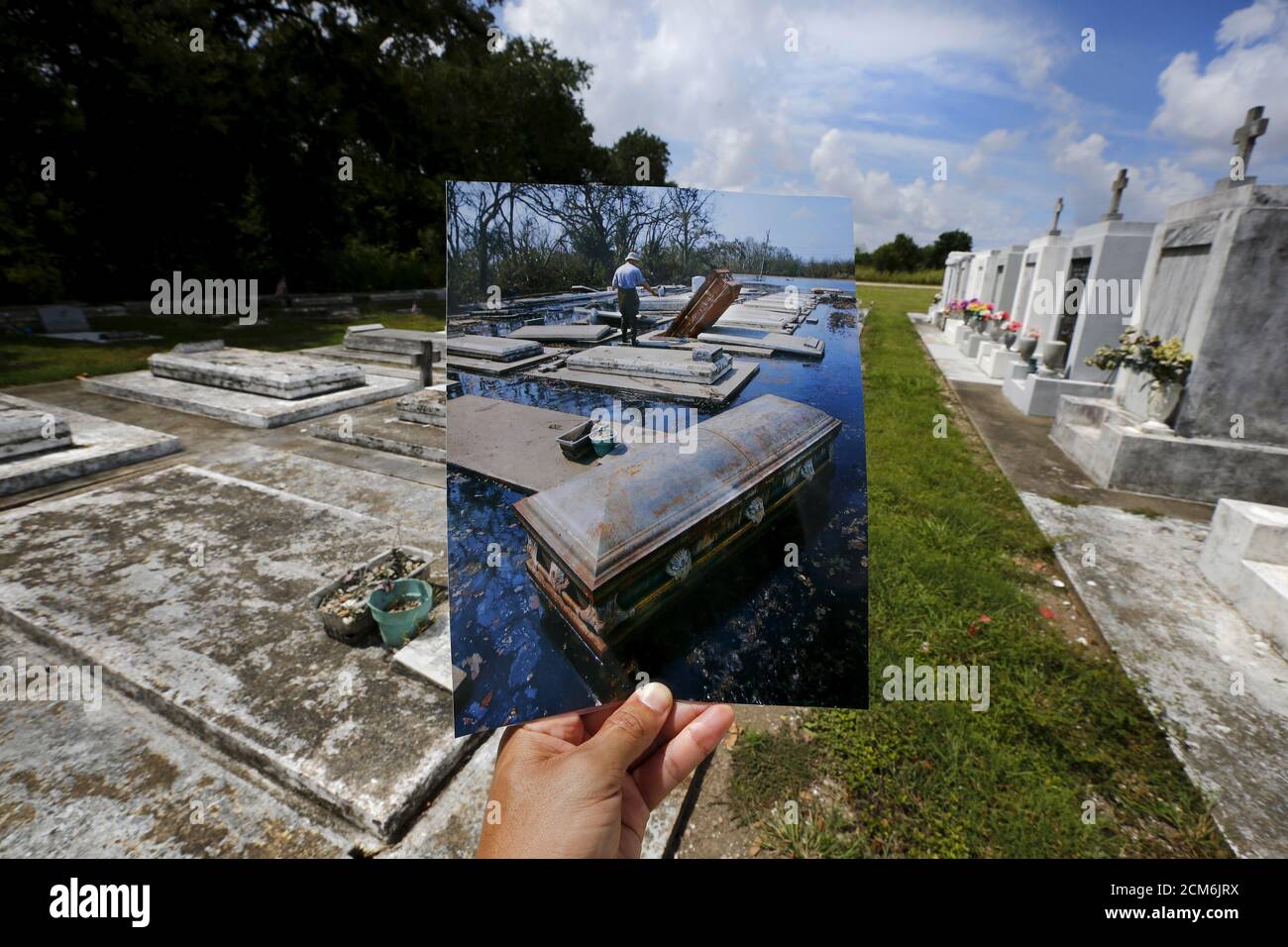 Photographer Carlos Barria holds a print of a photograph he took in 2005, as he matches it up at the same location 10 years on, in New Orleans, United States, August 18, 2015. The print shows coffins removed from tombs, September 10, 2005, after Hurricane Katrina struck. In 2005, Hurricane Katrina triggered floods that inundated New Orleans and killed more than 1,500 people as storm waters overwhelmed levees and broke through floodwalls. Congress authorised spending more than $14 billion to beef up the city's flood protection after Katrina and built a series of new barriers that include manmad Stock Photo