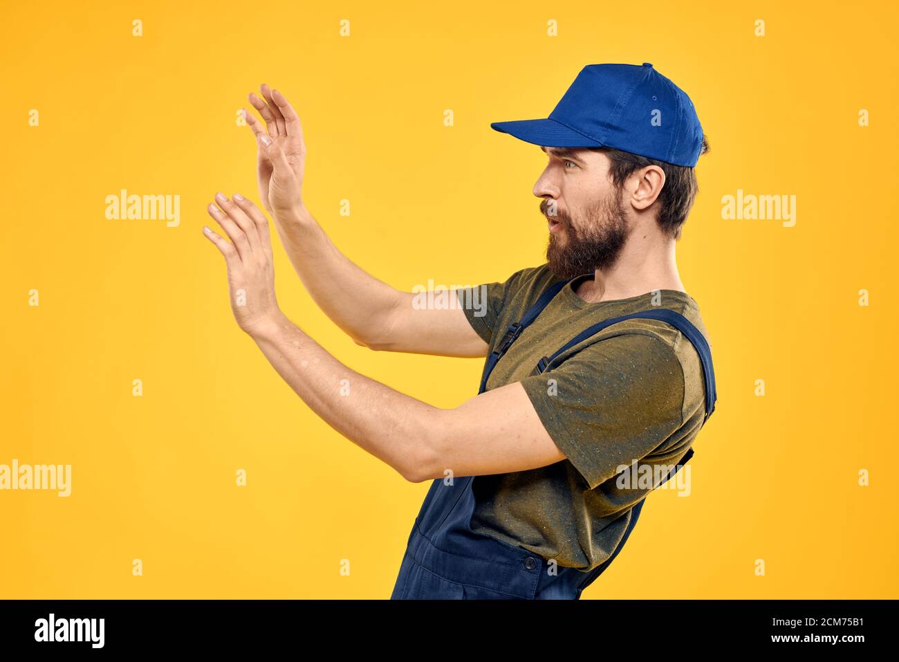 Worker man in uniform worker service yellow background emotion Stock