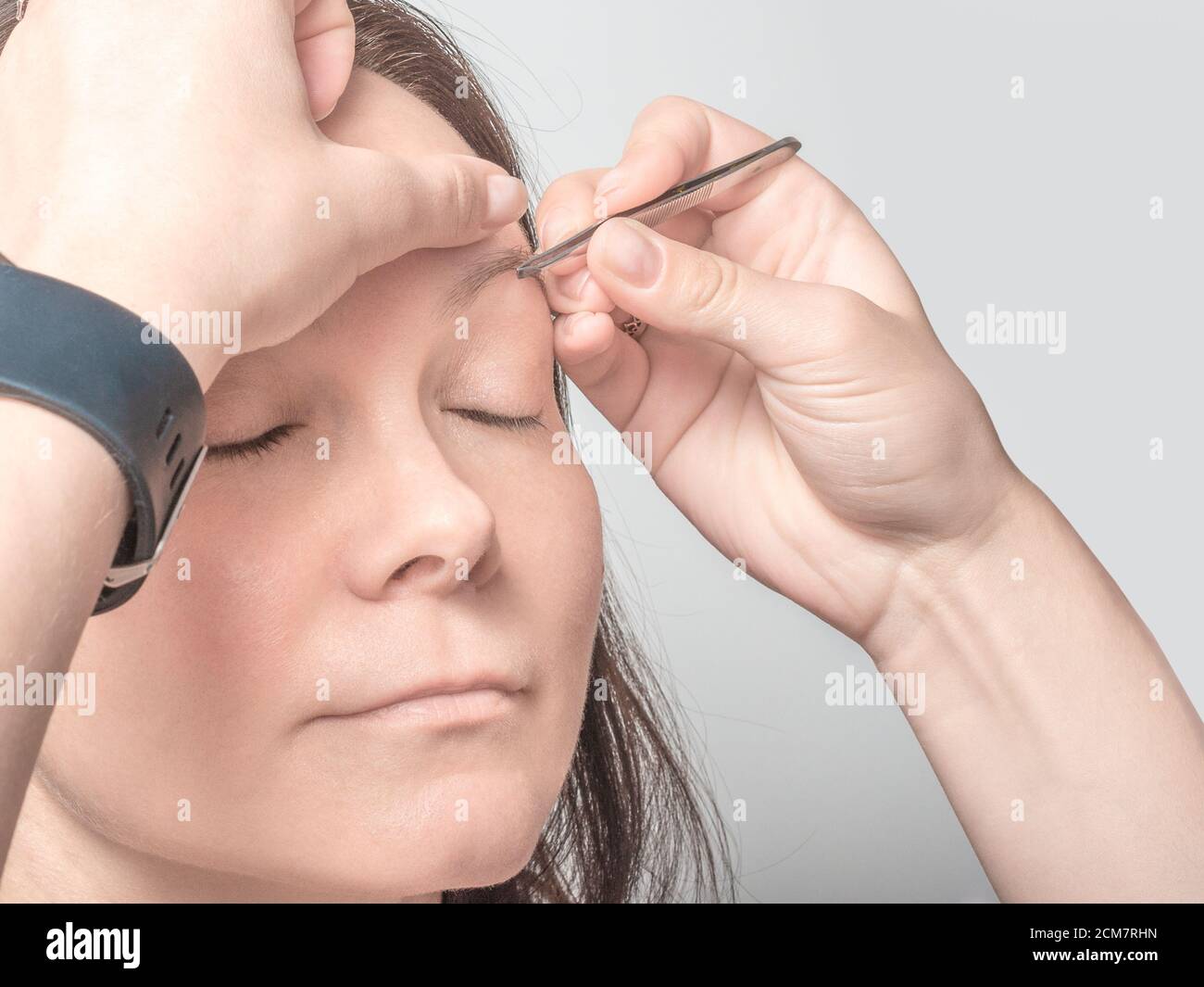 woman plucking eyebrows with tweezers close up Stock Photo Alamy
