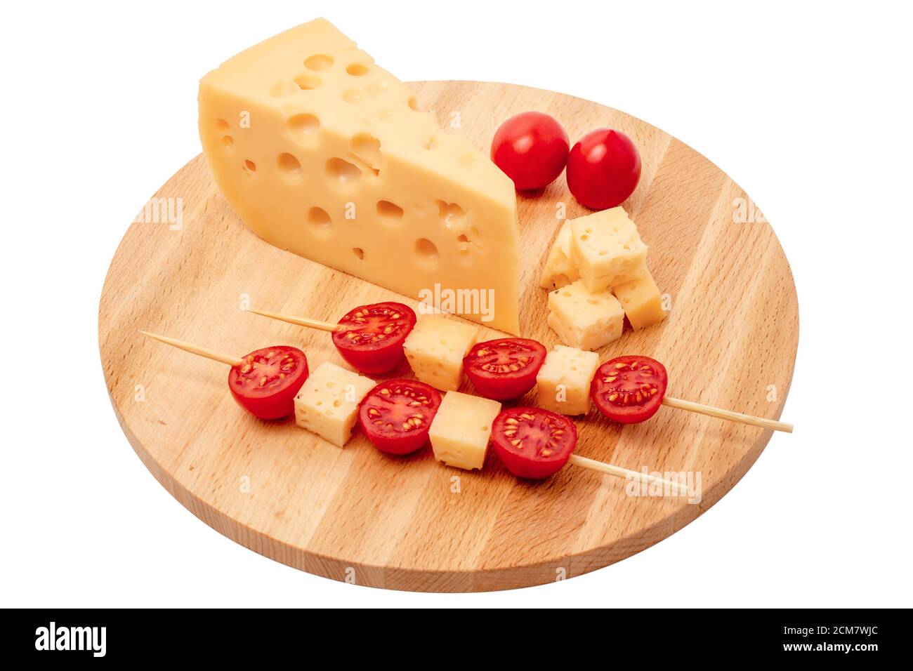 piece of cheese and cheese skewers with tomato on a wooden board, triangular cheese piece, cheese with holes cutout on white background Stock Photo