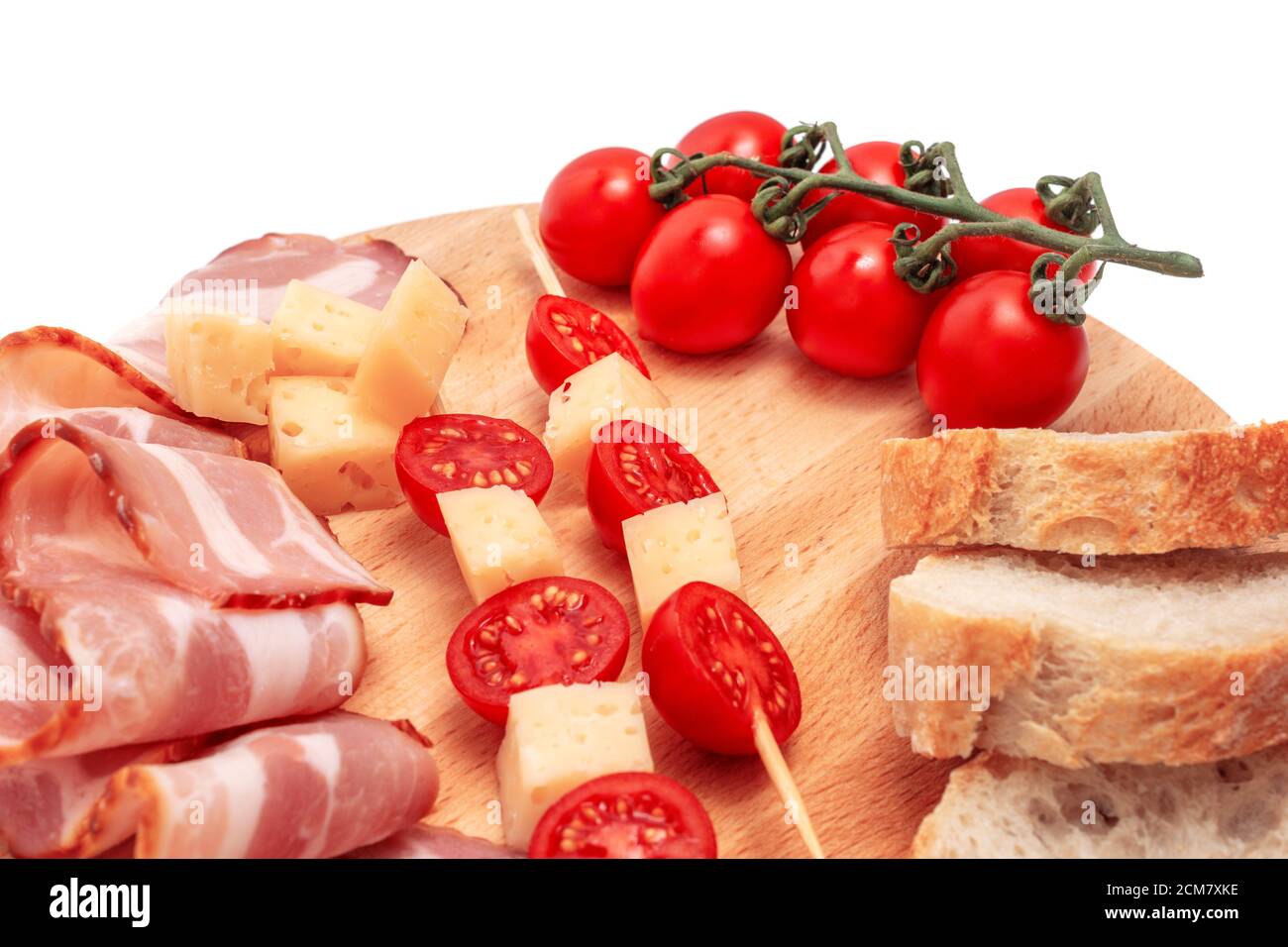 composition of cheese tomatoes bacon and bread on wooden board, isolated white background Stock Photo