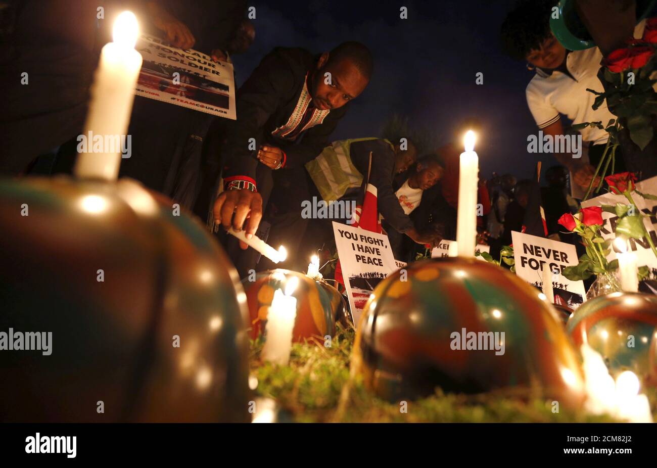 Kenyan activist Boniface Mwangi lights a candle near a replica of a gun and helmets placed on the ground to symbolise Kenyan soldiers serving in the African Union Mission in Somalia (AMISOM), who were killed during an attack last week, at a memorial vigil within the 'Freedom Corner' in Kenya's capital Nairobi, January 21, 2016. Al Shabaab, which is aligned with al Qaeda, said its fighters killed more than 100 Kenyan soldiers when they overrun the base in Ceel Cadde, near the Kenyan border, on Jan 15. REUTERS/Thomas Mukoya Stock Photo