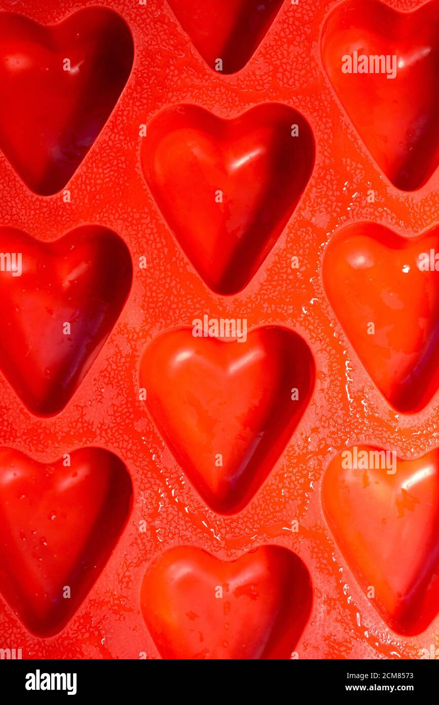 red hearts vertical background, silicone ice molds in the form of hearts. Bright red hearts abstract background Stock Photo