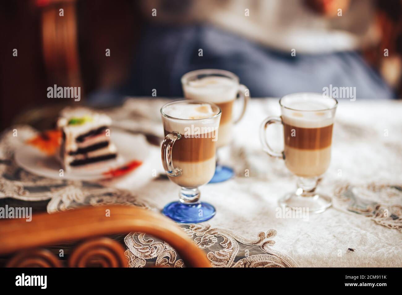 Glass mugs with delicious coffee on the table, sweet pastries, coffee