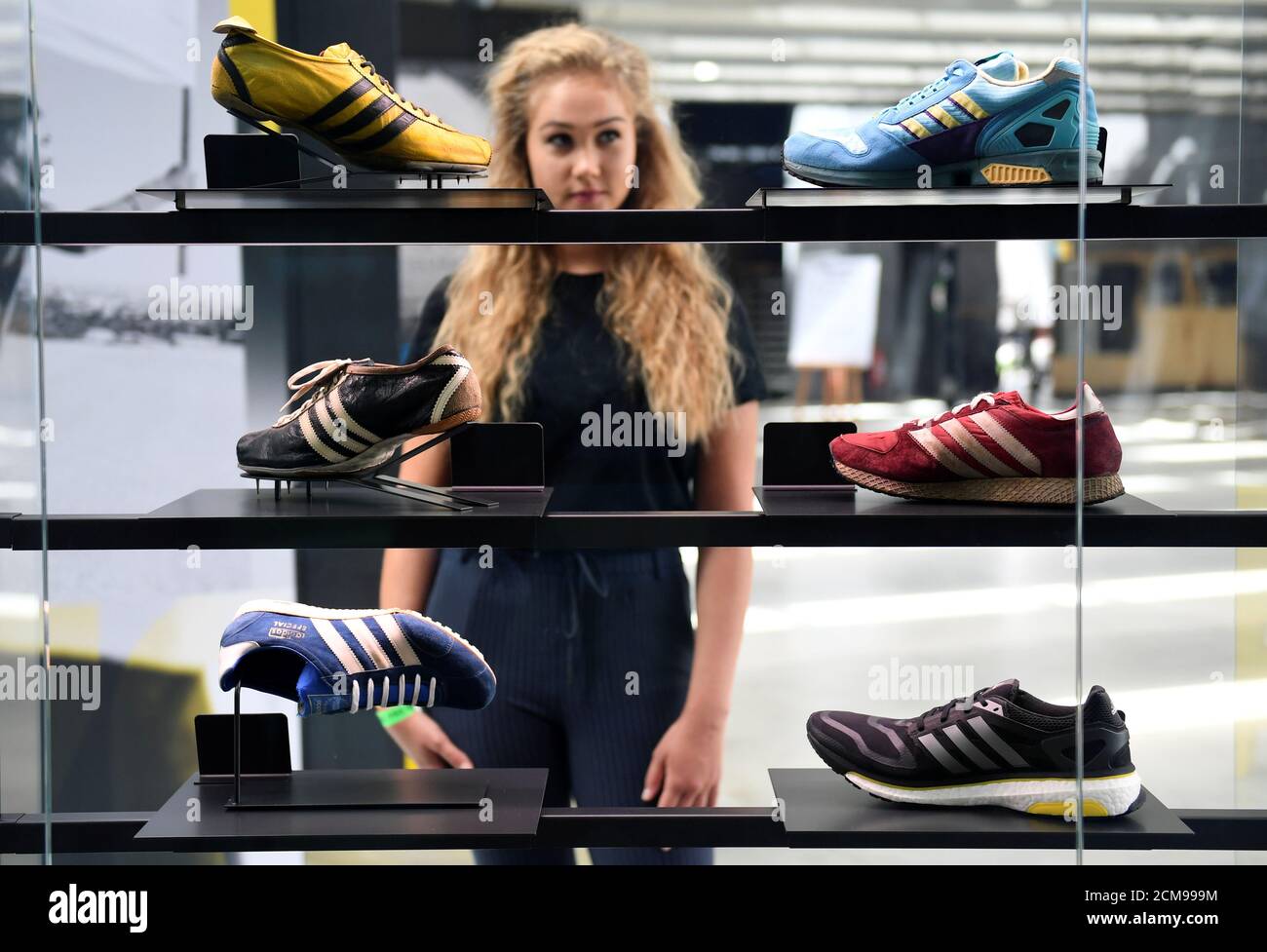 A woman poses in front of displayed Adidas shoes during celebrations for  German sports apparel maker Adidas' 70th anniversary at the company's  history exhibition in Herzogenaurach, Germany, August 9, 2019.  REUTERS/Andreas Gebert
