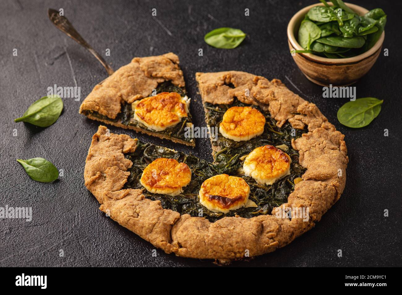 Rustic spinach and goat cheese galette on black background Stock Photo