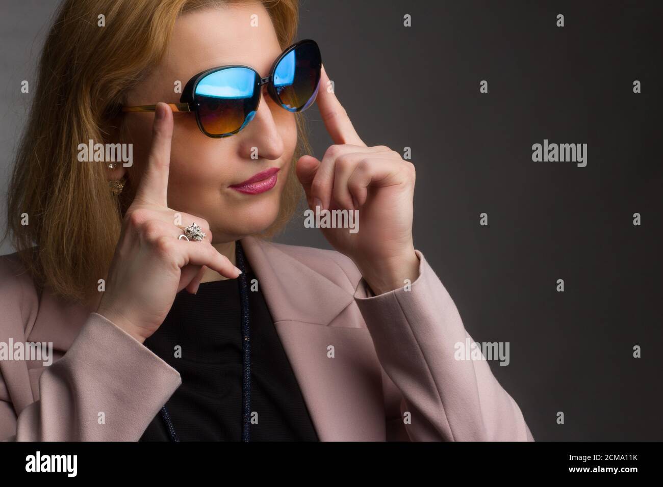 An overweight adult woman wearing sunglasses and black and pink clothing. Studio portrait on a black background Stock Photo