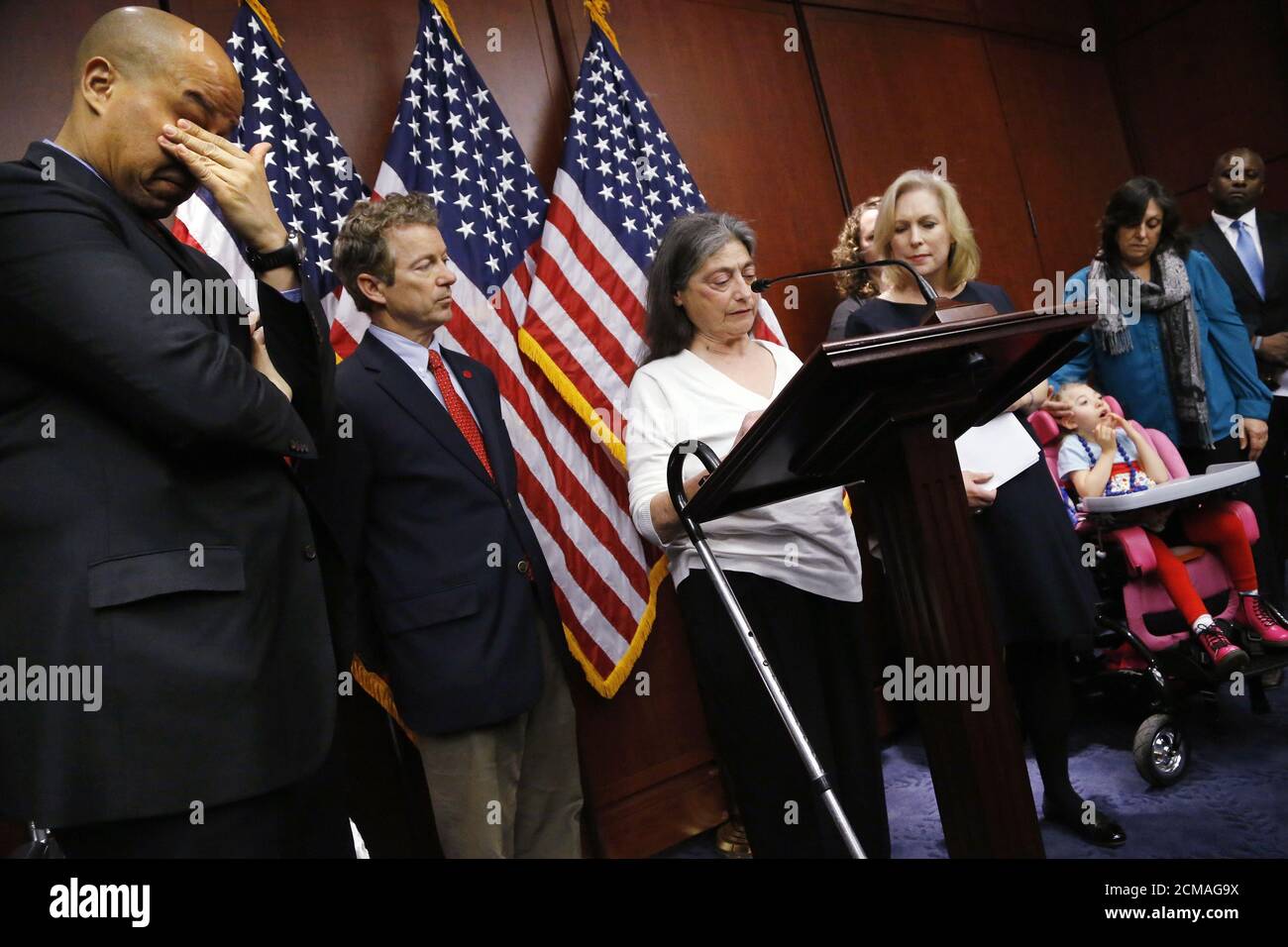 U.S. Senator Cory Booker (D-NJ) (L) wipes away tears as Sandy Faiola (3rd L), a medical marijuana patient from New Jersey, tells her story at a news conference to introduce legislation that would prevent the federal government from prosecuting medical marijuana users in states where it is legal, at the U.S. Capitol in Washington, March 10, 2015. Also pictured are the cosponsors of the legislation, Senator Rand Paul (R-KY) (2nd L) and Senator Kirsten Gillibrand (D-NY) (3rd R), as well as young epilepsy sufferer Morgan Jones (bottom R), age 4 of New York. REUTERS/Jonathan Ernst    (UNITED STATES Stock Photo