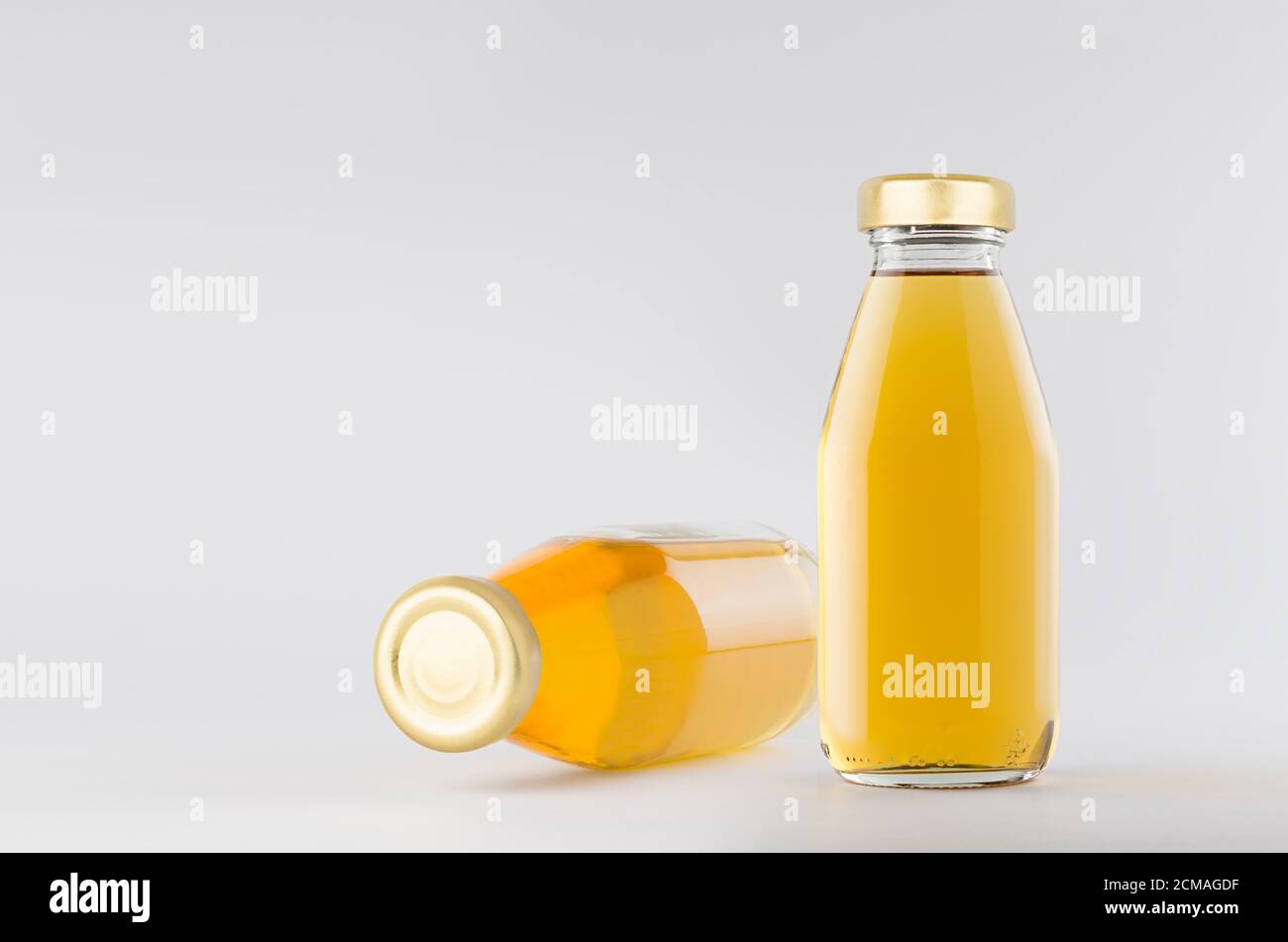 Yellow apple juices in glass bottles with gold empty cap for label mock up on white background with copy space, template for packaging, advertising, d Stock Photo