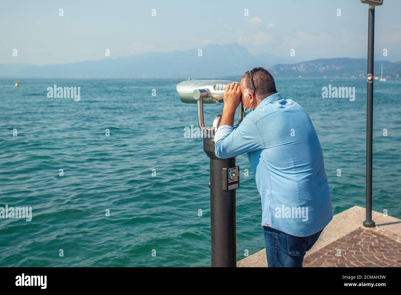 Man looks at binoculars on Garda Lake Stock Photo