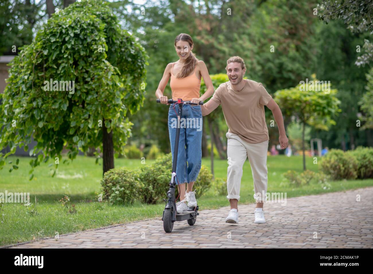 Young man teaching his girlfriend to ride a scooter Stock Photo Alamy