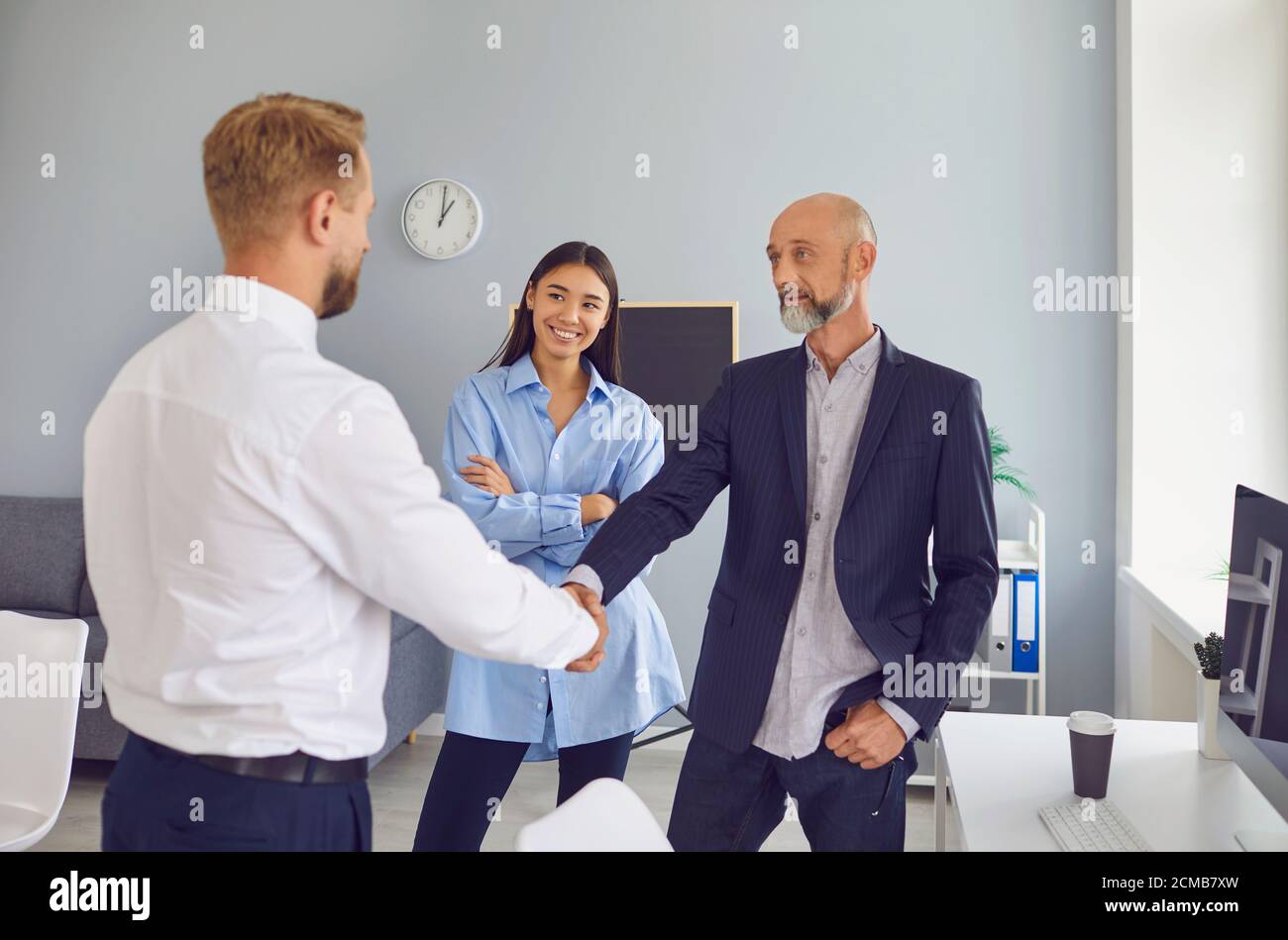 Friendly male company manager and aged client shaking hands confirming a business deal Stock Photo