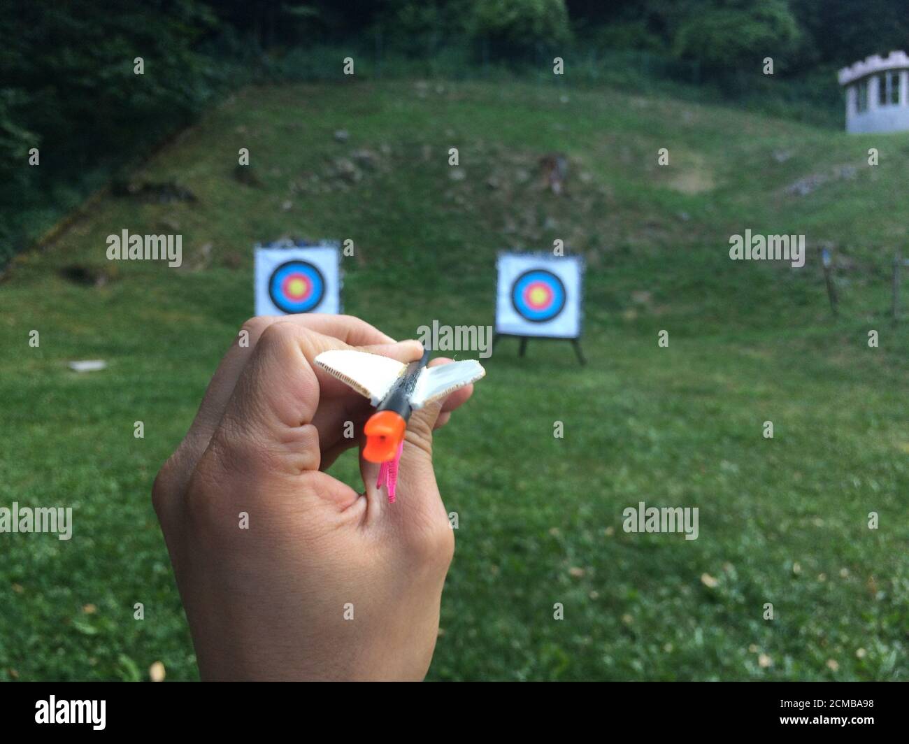 Selective focus shot of a person's hand holding an arrow and aiming at ...