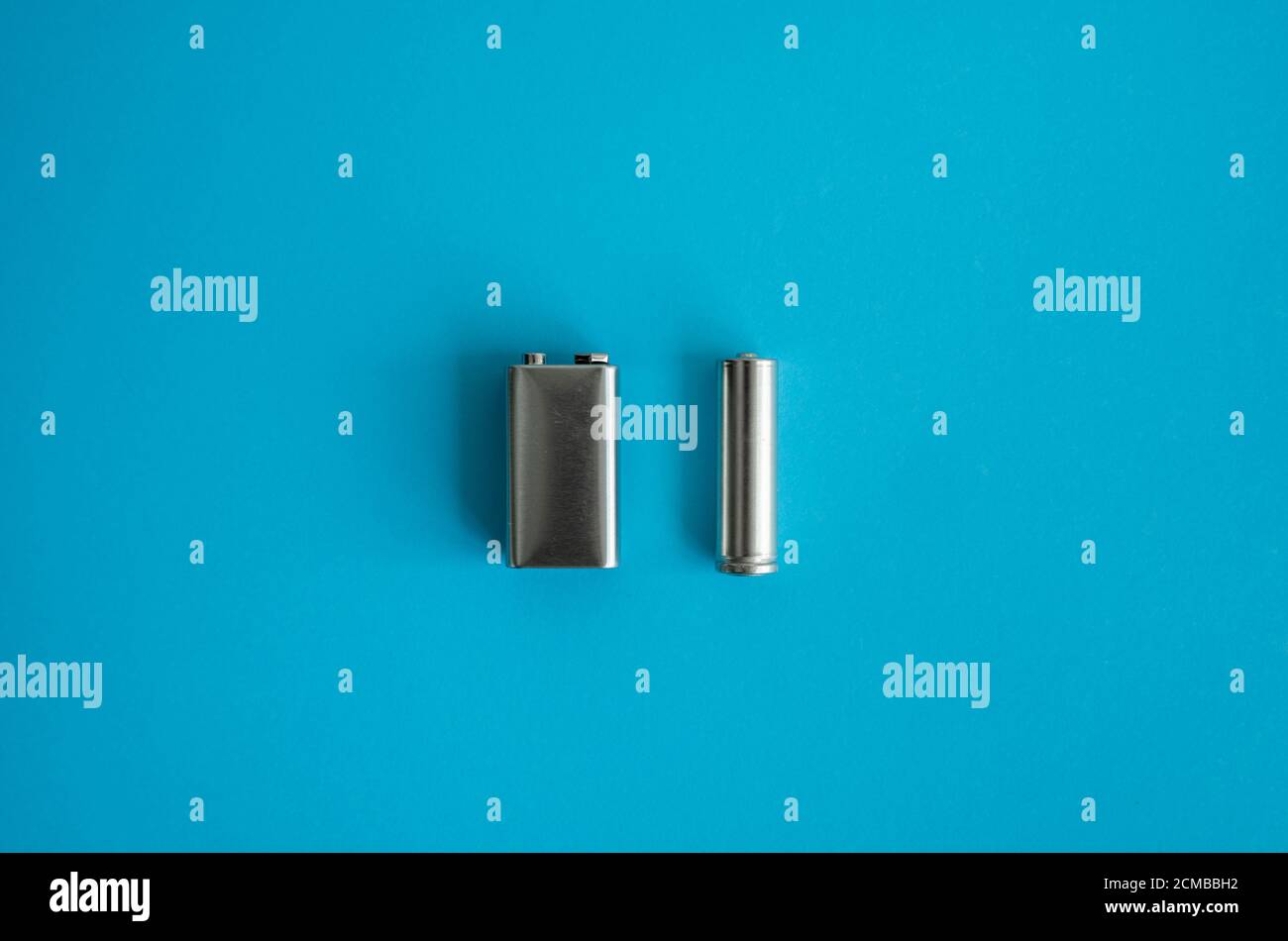 High voltage Volt 9V battery and alkaline AA battery on a blue background.  Energy Stock Photo - Alamy