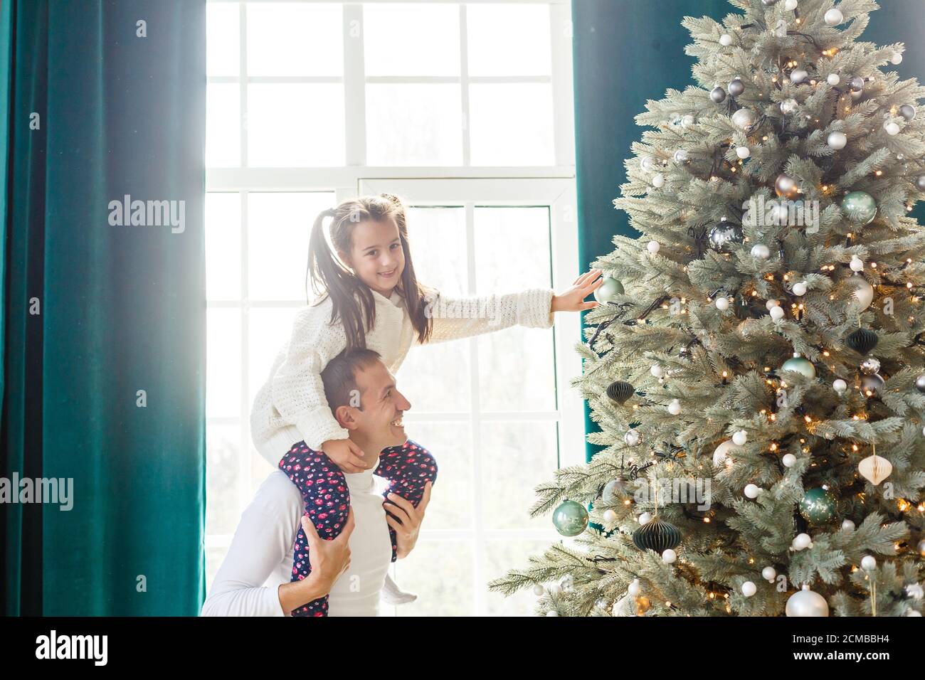 Happy father and his little daughter decorating the Christmas tree at ...