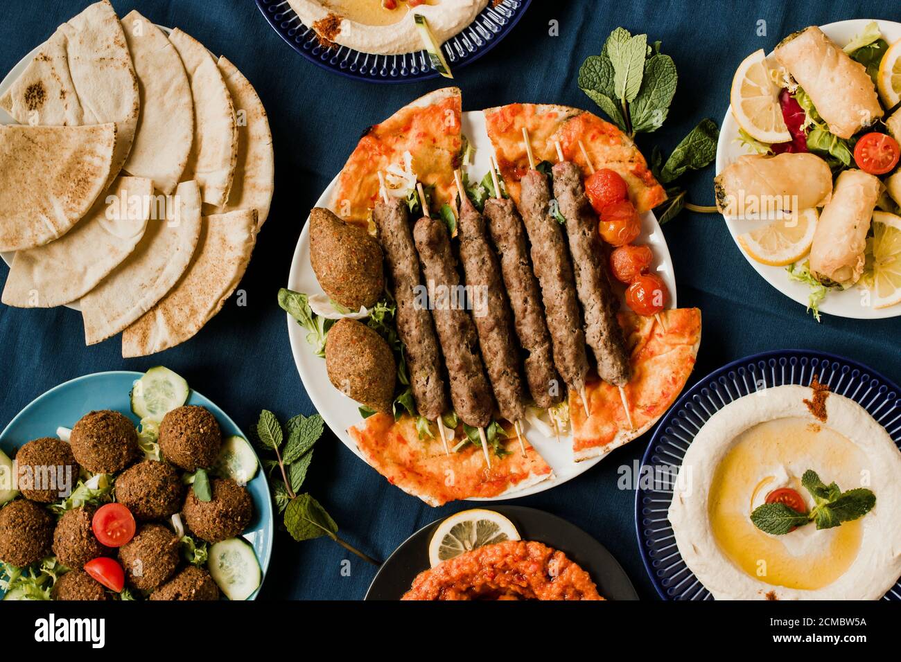 Traditional Arab cuisine including kebab meat, kibbeh, mutabal, falafel, muhammara, pita bread and hummus Stock Photo