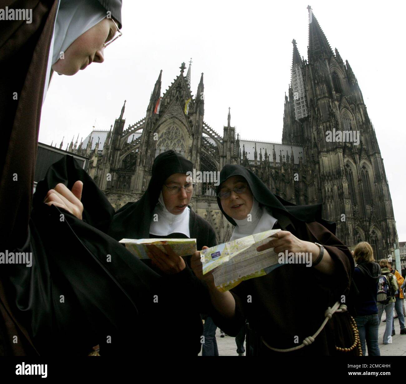 Four nuns from Muenster in Westphalia look at their city maps after arriving for the World Youth Day in Cologne.  Four nuns from Muenster in Westphalia look at their city maps after arriving for the World Youth Day in Cologne August 15, 2005. The World Youth Day takes place in the western German city from August 16 until August 21, 2005. In the background is the Cologne Cathedral. REUTERS/Arnd Wiegmann Stock Photo