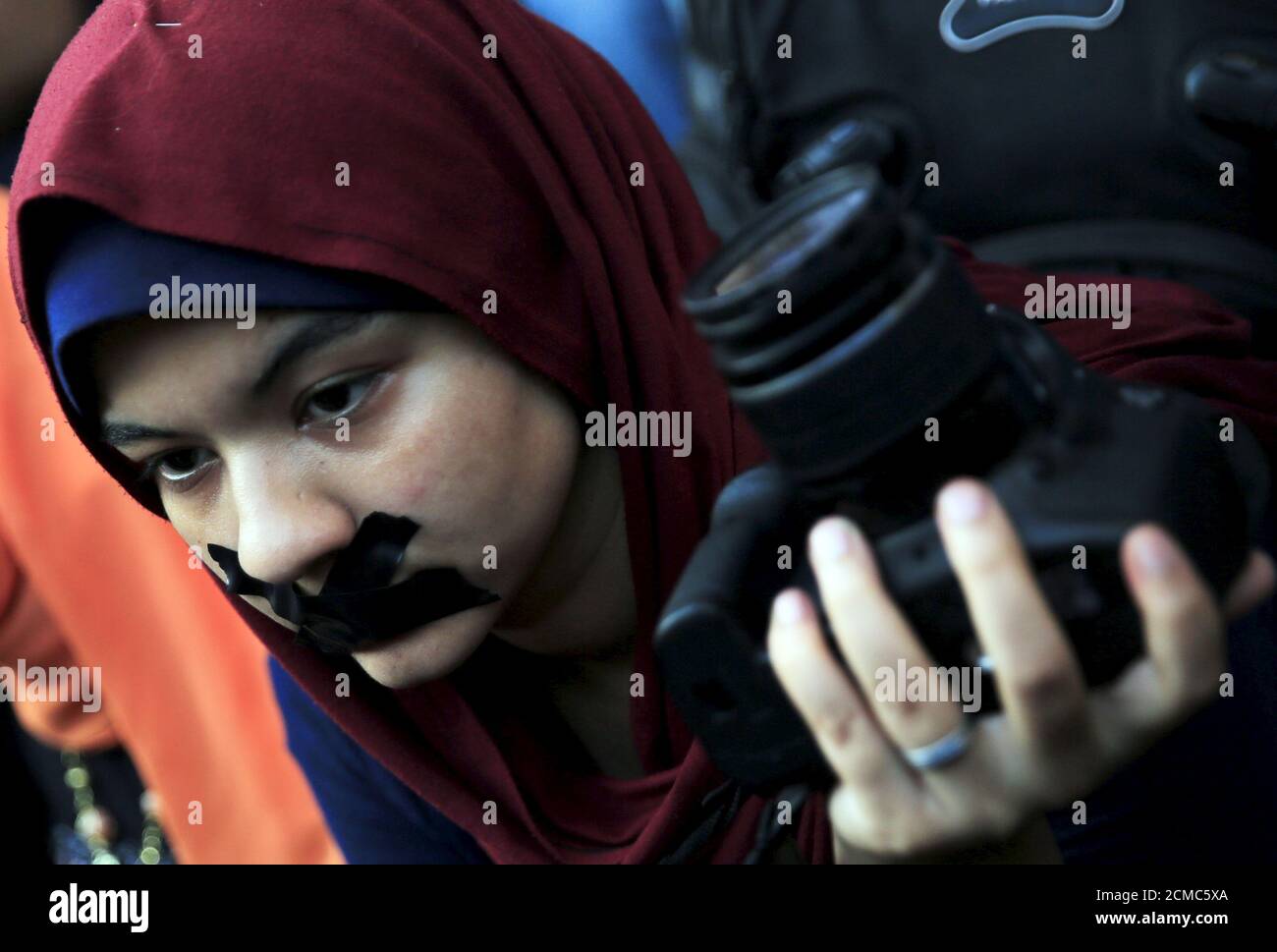 A news photographer with her mouth taped and holds up her camera during a protest against the detention of Ahmed Ramadan, a photojournalist with Egyptian private newspaper 'Tahrir', in front of the Syndicate of Journalists in Cairo, Egypt August 17, 2015.  Ramadan was released on bail late Monday following his arrest on Sunday on accusations that he was a member of the Muslim Brotherhood, local media reported. Egyptian President Abdel Fattah al-Sisi approved an anti-terrorism law that sets up special courts and protects its enforcers in the face of a two-year-old Islamist insurgency that aims  Stock Photo