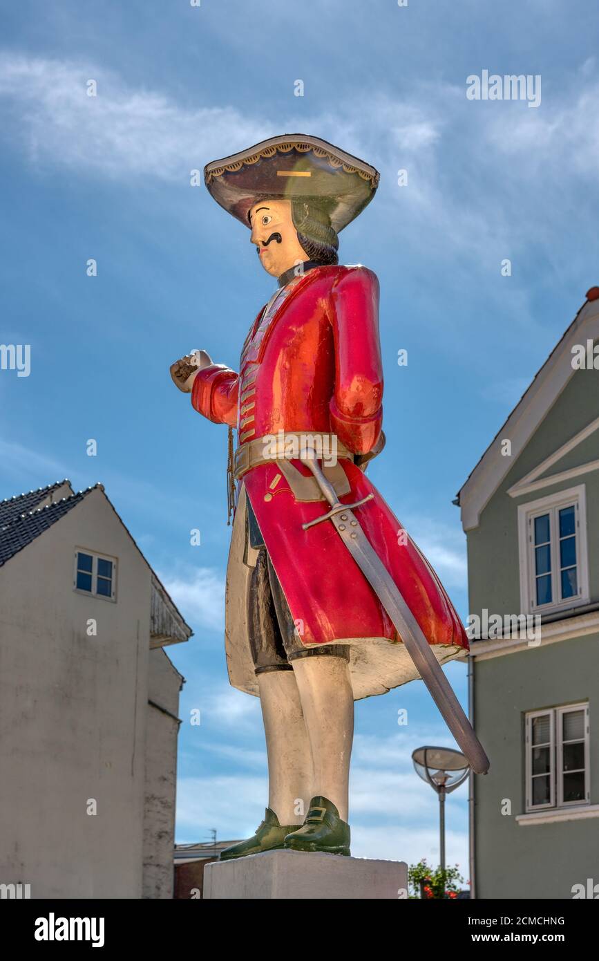 A soldier-like whipping post in a rede robe and big hat standing in the square of Tønder, equipped with a sword and a whip , Denmark, June 1, 2020 Stock Photo