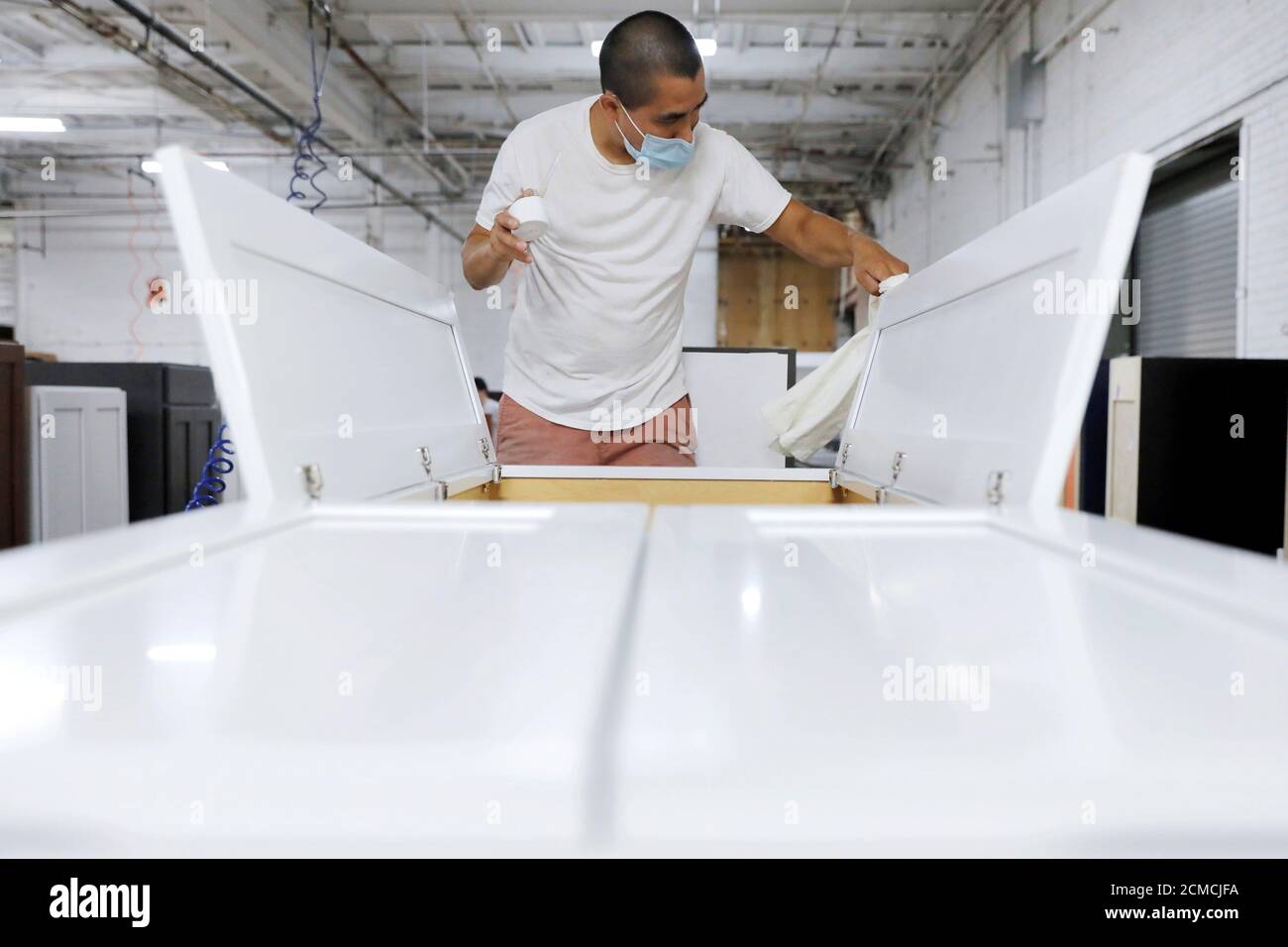 A worker checks a cabinet before it is packed at CNC Cabinetry in South Plainfield, New Jersey, U.S., June 16, 2020. REUTERS/Andrew Kelly Stock Photo