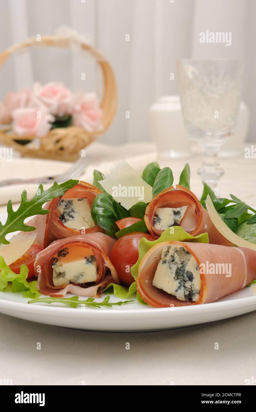 Rolls of jamon with blue cheese in lettuce leaves and parmesan Stock Photo