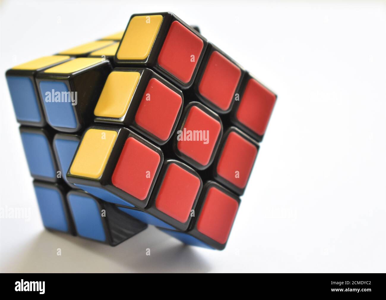 An isolated Rubik's Cube puzzle sits almost solved on a crisp white