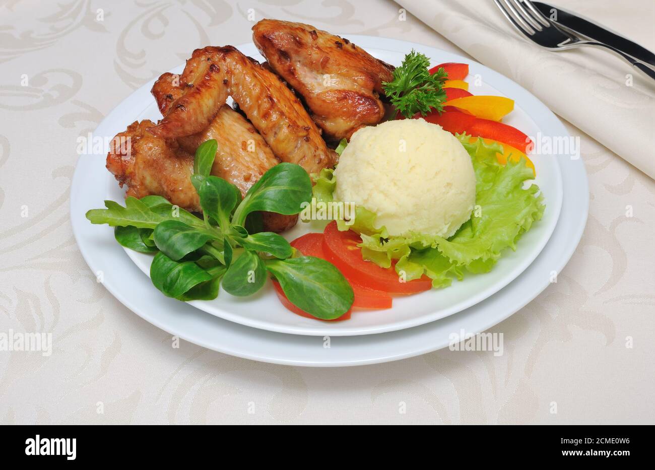 Baked chicken wings with garlic and potatoes and vegetables Stock Photo