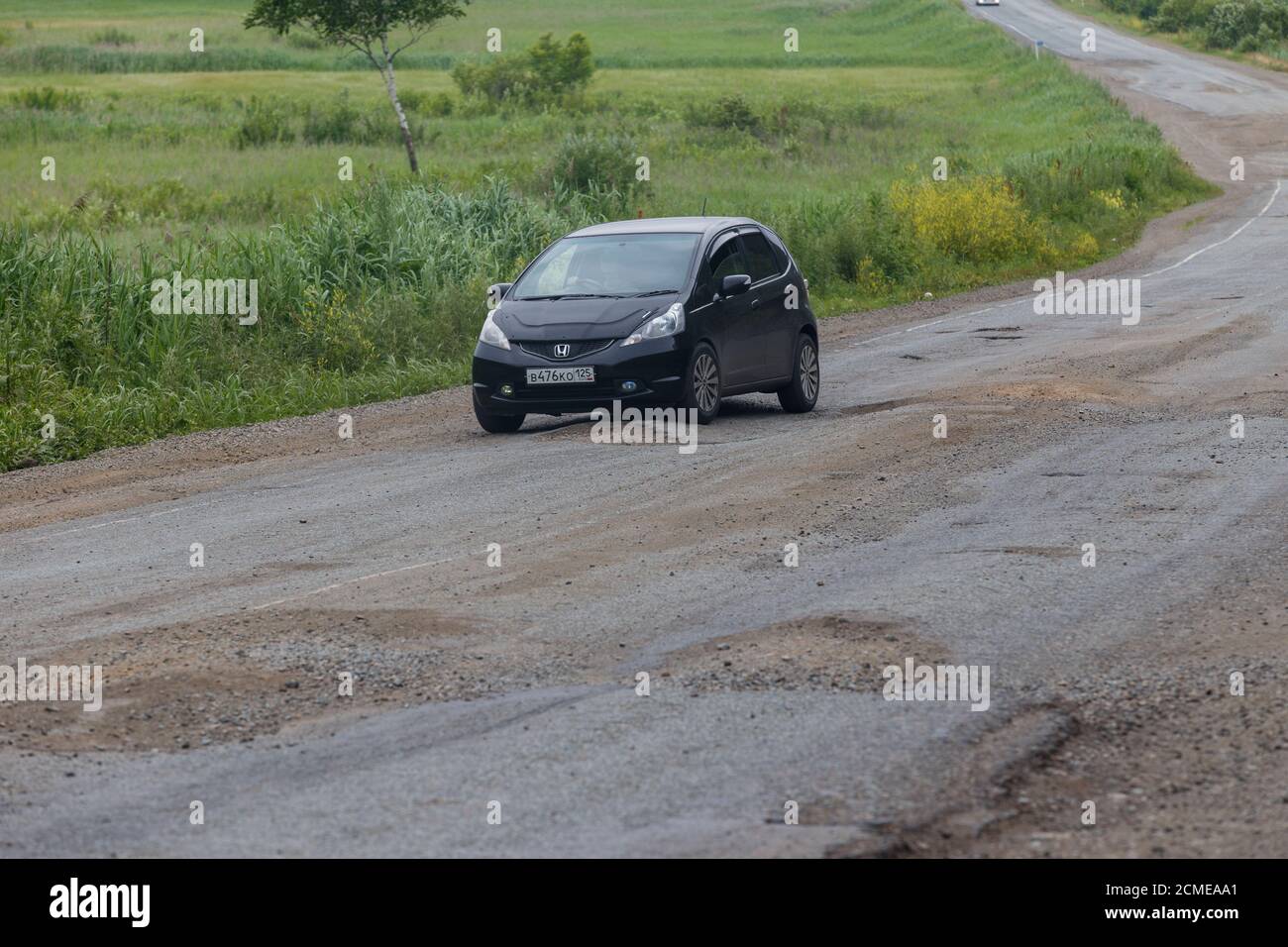 The car drives on a bad asphalt road. Killed Russian roads Stock Photo