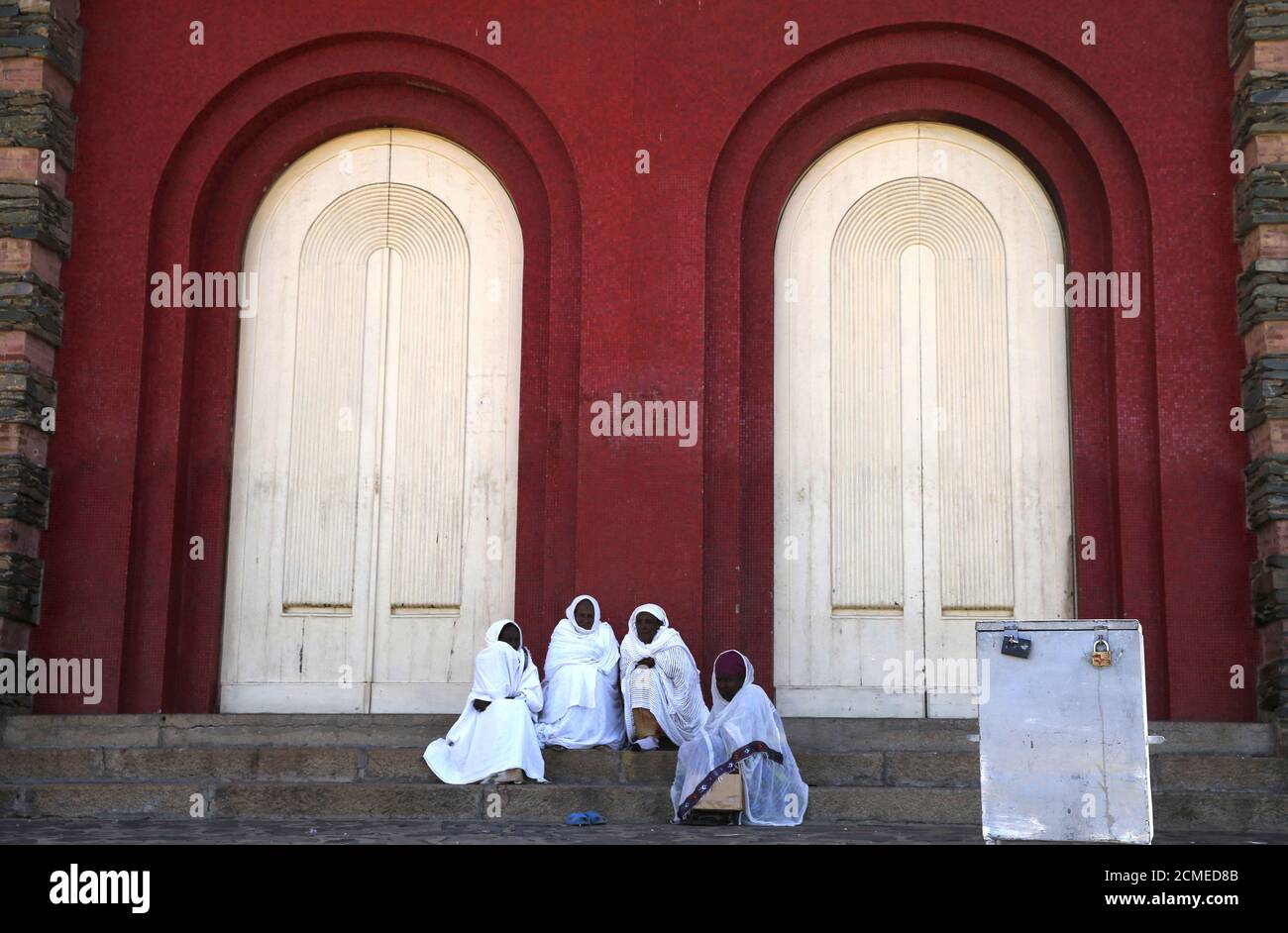 Faithful sit outside the Nda Mariam Orthodox Cathedral in Eritrea's capital Asmara, February 16, 2016. Eritrea's capital city boasts one of the world's finest collections of early 20th century architecture, which the authorities want declared a UNESCO World Heritage Site. When Italy's colonial experiment in Eritrea ended in 1941, it left behind an array of Rationalist, Futurist, Art Deco and other styles of Modernism in Asmara, a city they nicknamed 'La Piccola Roma' or 'Little Rome'. REUTERS/Thomas Mukoya SEARCH 'THE WIDER IMAGE' FOR ALL STORIES Stock Photo