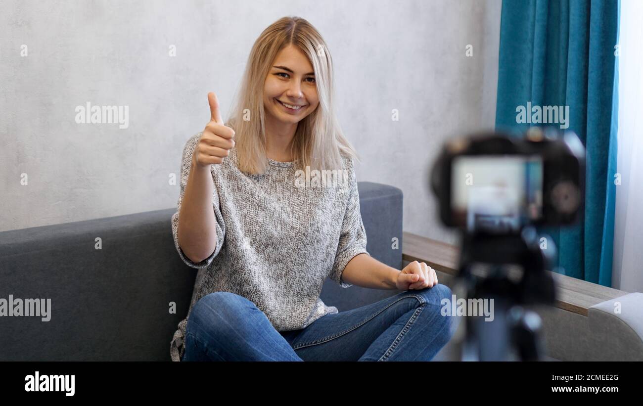 Wwoman or blogger with camera recording video and showing thumbs up at home Stock Photo
