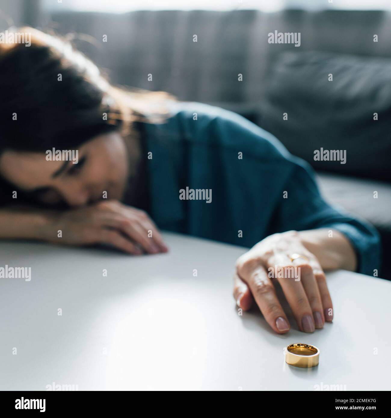 Sadly Reaching selective focus of sad woman reaching golden ring on coffee table ...
