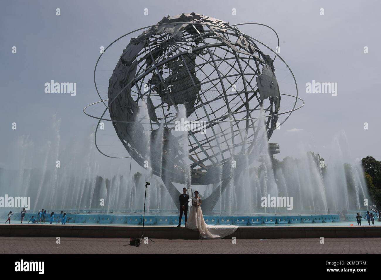 A bride and groom pose for pictures at the Unisphere in Flushing Meadows Park in the Queens borough of New York City, U.S., July 9, 2019.  REUTERS/Shannon Stapleton Stock Photo