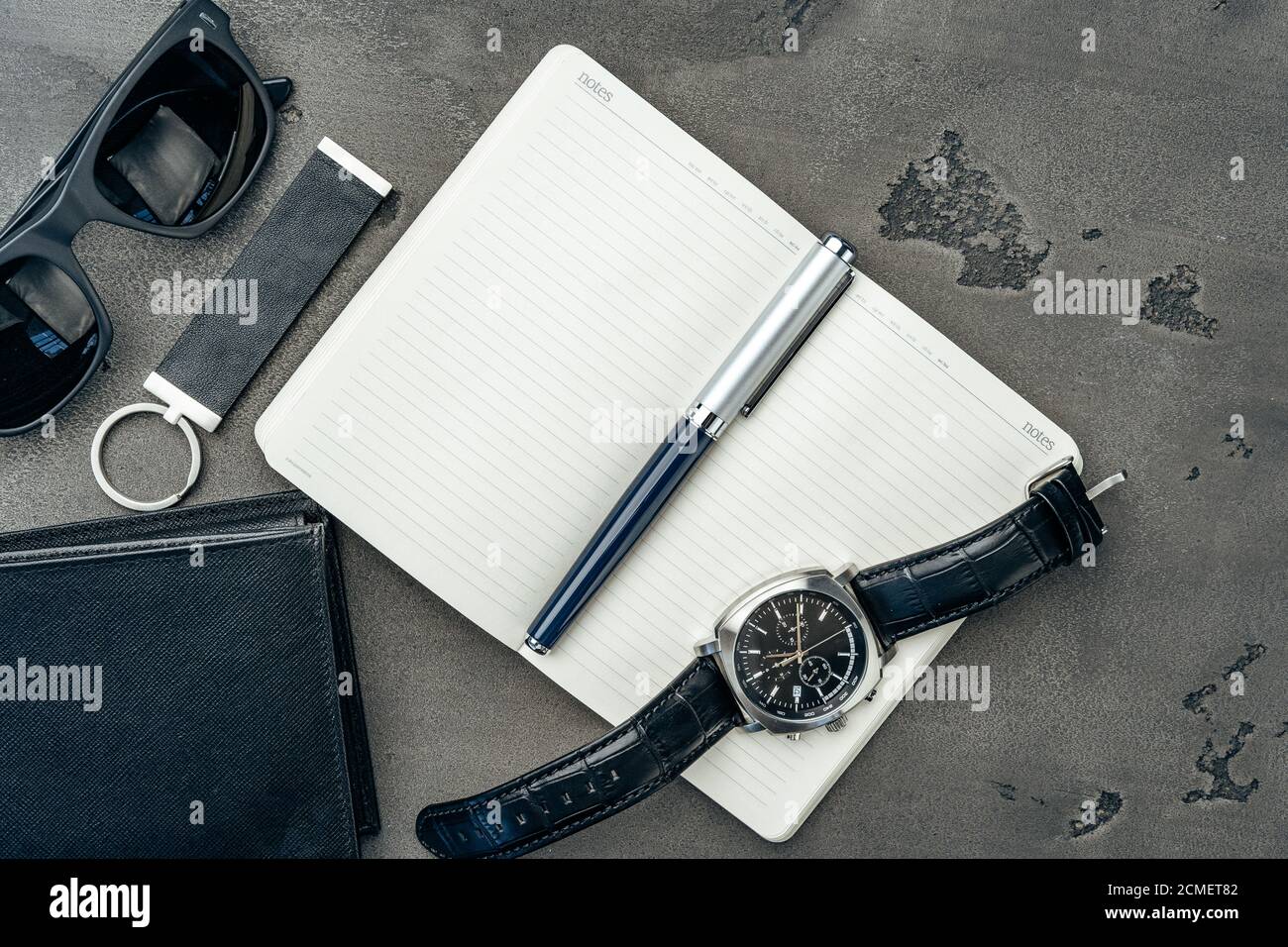 Businessman's accessories including notepad, watch and purse on dark grey background Stock Photo